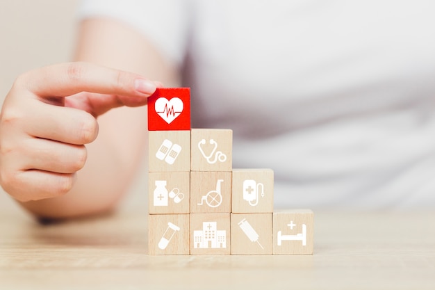 Bloque de madera del seguro médico que apila con la asistencia sanitaria del icono médica.