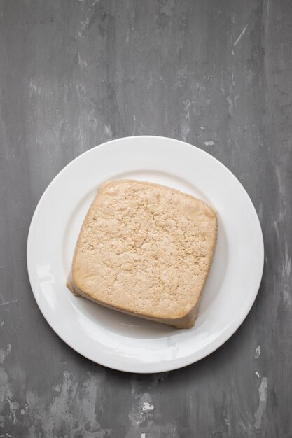 Bloque de tofu crudo en plato pequeño blanco sobre cerámica