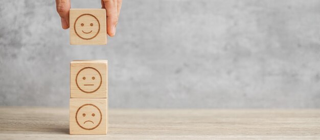 Bloqueo facial de emoción de mano. El cliente elige Emoticon para las reseñas de los usuarios. Calificación del servicio, clasificación, revisión del cliente, satisfacción, estado de ánimo, evaluación y concepto de retroalimentación