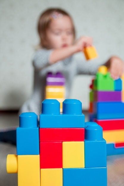 Bloques de construcción de plástico brillante con niña niño irreconocible en el fondo. Desarrollando juguetes. Aprendizaje temprano.