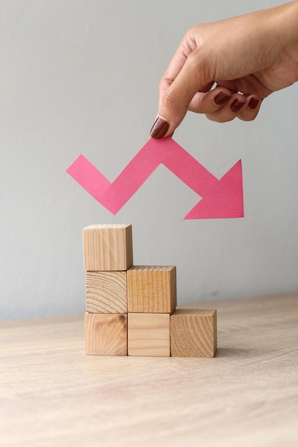 Bloques de madera y una flecha gráfica apuntando hacia abajo. El concepto de colapso económico.