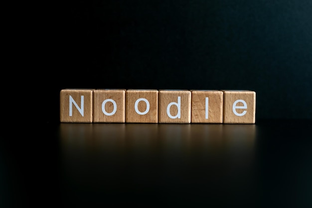 Foto los bloques de madera forman el texto noodle contra un fondo negro
