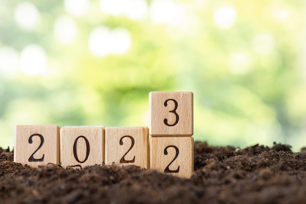 Los bloques de madera yacen sobre una mesa de madera con el telón de fondo de un jardín de verano y crean la palabra 2023