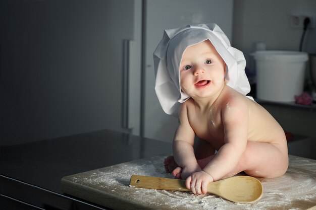 Bloßer Babybäcker mit Kochmütze in der Küche, Kopierraum