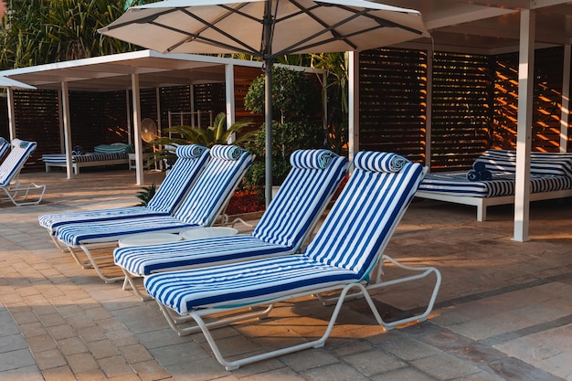 Blue Bed Pool mit Handtuchständer unter offenen Sonnenschirmen vor dem Hintergrund einer wunderschönen Palmenruhe