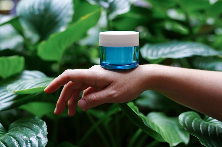 Foto a blue jar with cosmetic cream staying on female hand green leaves nature background skin care