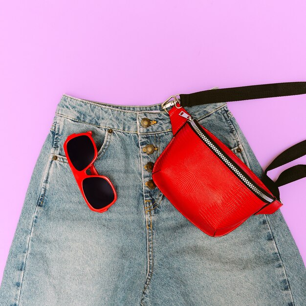 Blue jeans y complementos rojos de moda. Bolso de mano y gafas de sol