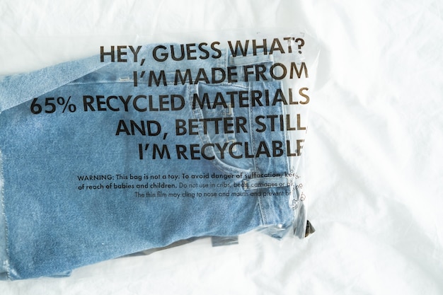 Blue Jeans in Plastiktüte mit Etikett aus recycelten Materialien und recycelbar. Zero-Waste-Konzept.