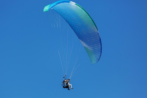 Blue Paraglider voando para o céu com nuvens em um dia ensolarado