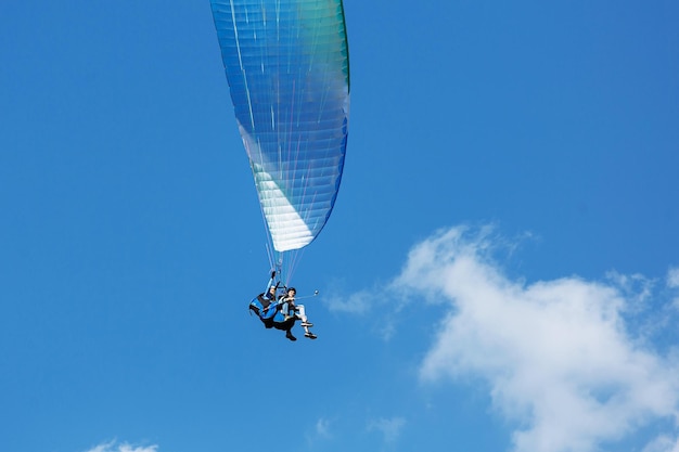 Blue Paraglider voando para o céu com nuvens em um dia ensolarado