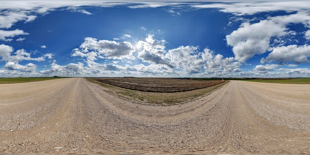 Foto blue sky hdr 360 panorama mit atemberaubenden wolken auf einer schotterstraße zwischen feldern an einem frühlingstag in einer rechteckigen vollen nahtlosen kugelförmigen projektion für vr-ar-inhalte oder skydome-ersatz