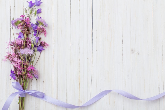 Bluebel Blumen om weißen hölzernen Hintergrund