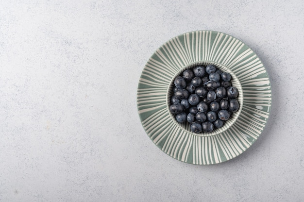 Blueberries em uma tigela em um prato sobre uma luz de madeira