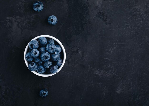 Blueberry Arándanos orgánicos frescos en un tazón sobre fondo de piedra oscura