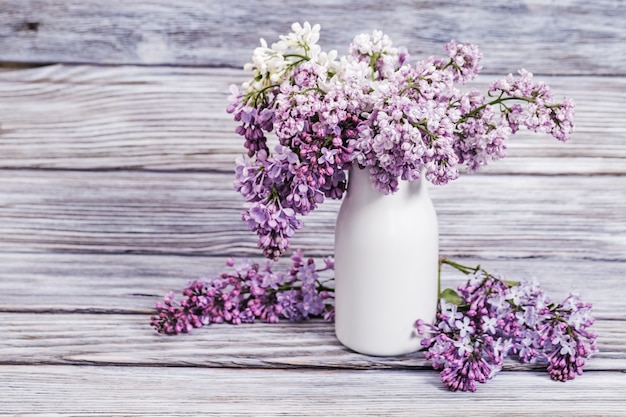 Blühende lila Blumen im weißen Vase auf Holz