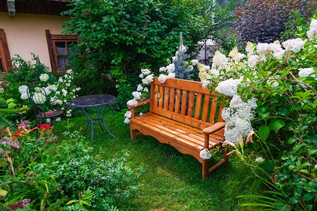 Blühender Garten im Innenhof eines Landhauses mit einer Holzbank, großen weißen Blumen