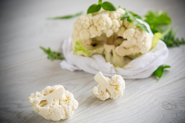 Blütenstände von kleinem rohem Blumenkohl auf einem hellen Holztisch