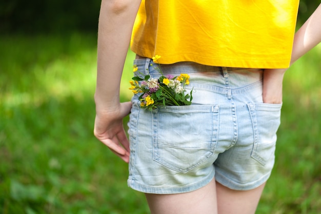 Blume in einer großen Tasche der Jeanshose, Sommerkonzept