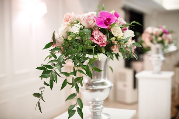 Blumen bei der Hochzeit im Design des Restaurants. Luxus Hochzeitsdekoration mit Rosen und bunten Orchideen