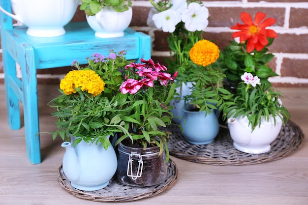 Blumen in dekorativen Töpfen auf Stuhl auf Ziegelsteinhintergrund