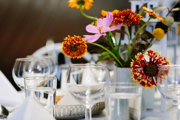 Blumen in einer Vase neben Gläsern auf dem Tisch