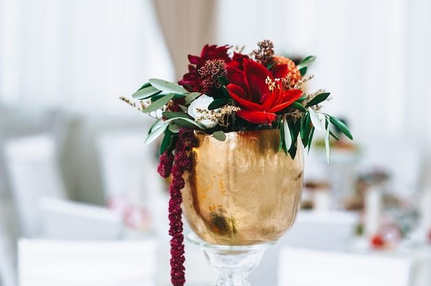 Blumen in kleinen Vasen der goldenen Farbe auf einem Hochzeitstisch. Restaurant vor der Hochzeit.