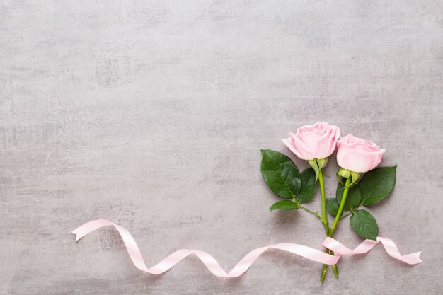 Blumen Valentinstag Zusammensetzung. Rahmen aus rosa Rose auf grauem Hintergrund. Flache Lage, Draufsicht, Kopierraum.