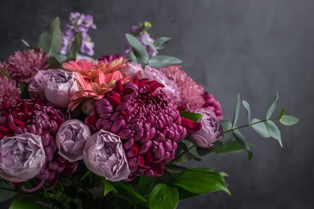 Blumenarrangement aus Chrysanthemen und Rosen auf dunklem Hintergrund