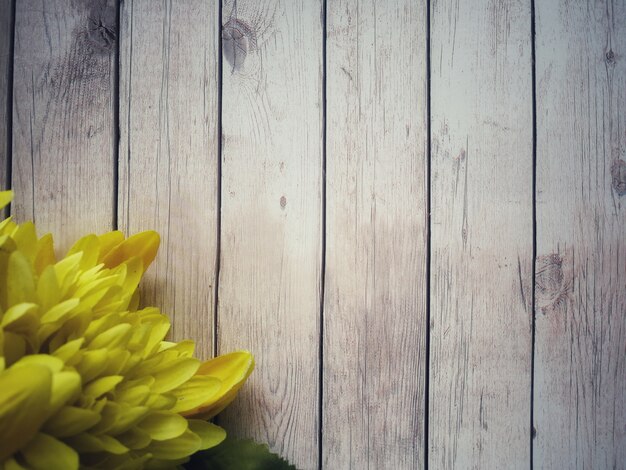 Blumengelb werden auf weißen Holztisch gelegt.