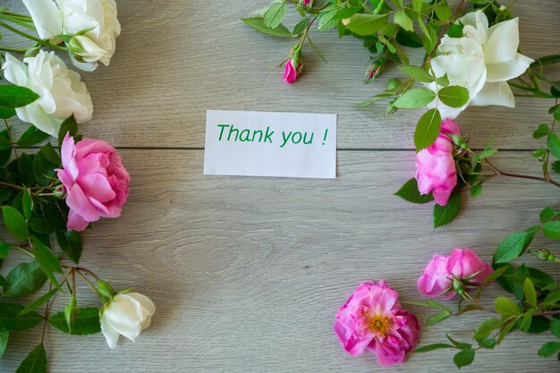 Blumenhintergrund aus rosa und weißen Rosen auf einem hellen Holztisch