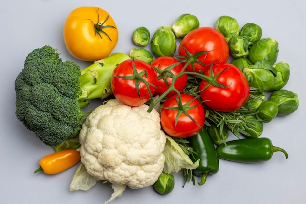 Blumenkohl, Brokkoli und ein Zweig roter Tomaten. Flach liegen. Grauer Hintergrund.