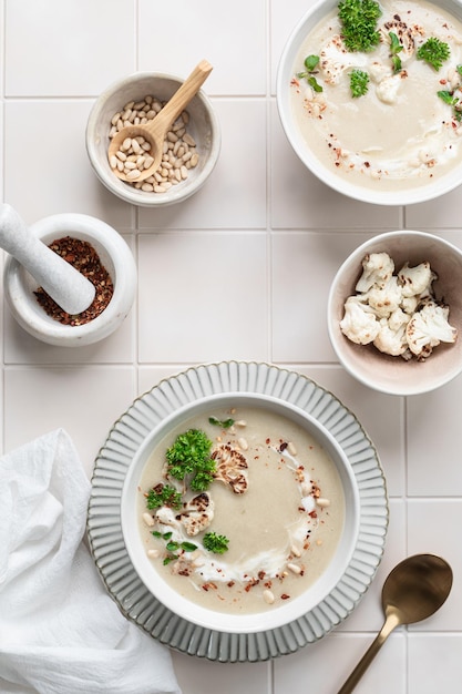 Foto blumenkohl-creme-suppe mit kiefernüssen in einer schüssel auf weißem hintergrund
