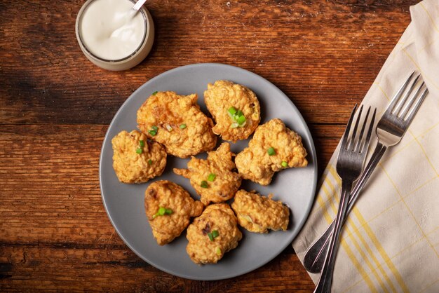 Blumenkohl-Wings-Essen Stücke von in Mehl gebratenem Blumenkohl mit veganen Saucen auf einem Teller Holzhintergrund Vegetarisches Essen