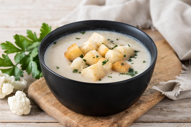 Blumenkohlsuppe in einer Schüssel auf einem Holztisch