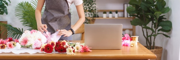 Blumenkonzept Blumenhändlerin wickelt und erstellt farbenfrohen Blumenstrauß mit Papier und Bandbogen