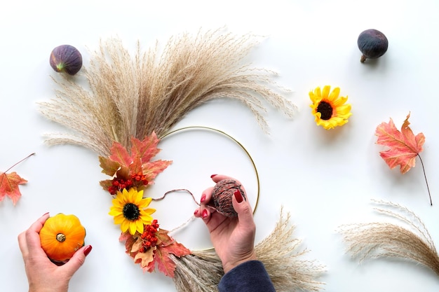 Blumenkranz aus trockenem Pampasgras und Herbstlaub Hände binden Dekorationen an Metallrahmen