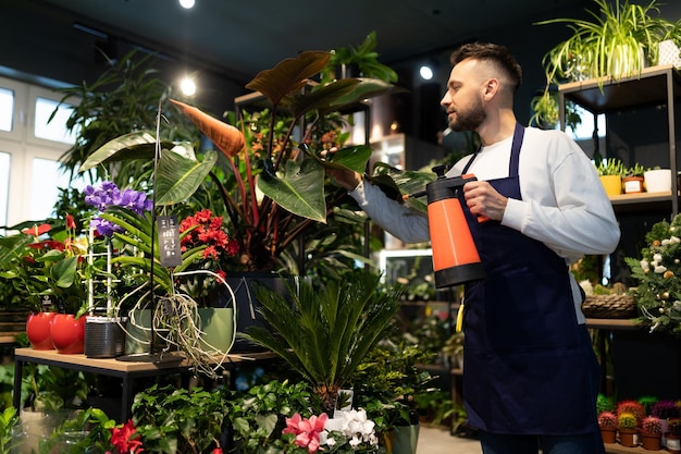 Blumenladenarbeiter, der Blumen in den Regalen gießt