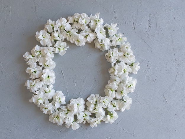 Blumenrahmen mit kleinen weißen Blumen auf grauem Tisch.