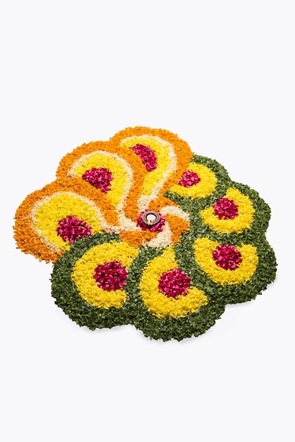 Blumenrangoli für Diwali oder Pongal aus Ringelblumen- oder Zendublumen und roten Rosenblättern auf weißem Hintergrund mit Tonöllampe in der Mitte, selektiver Fokus