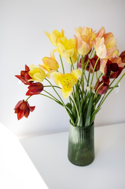 Blumenstrauß aus bunten Tulpen in einer grünen Vase. Frische Frühlingsblumen, Blumenhintergrund. Urlaubskonzept.