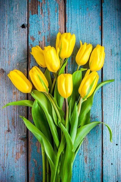 Blumenstrauß aus gelben Tulpen auf einem blauen rustikalen Hintergrund