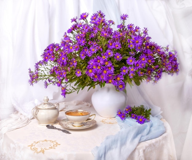 Blumenstrauß aus herbstlichen lila Astern in einer Vase auf weißem Hintergrund
