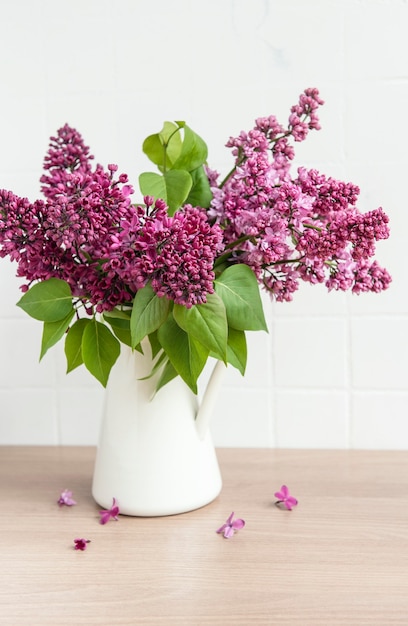 Blumenstrauß aus lila Blumen in einer Vase auf einem Holztisch.