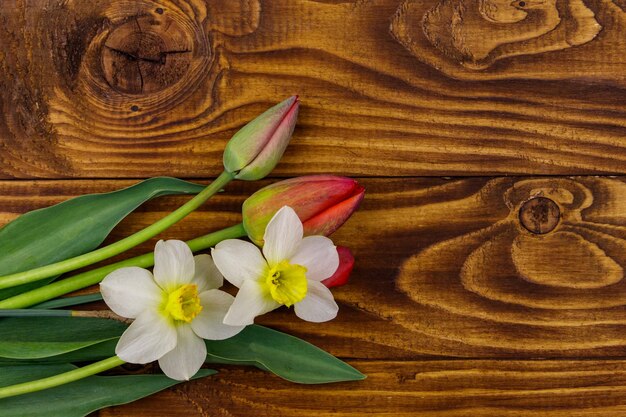 Blumenstrauß aus Narzissen und roten Tulpen auf Holzhintergrund Grußkarte für Ostern, Valentinstag, Frauentag und Muttertag