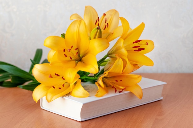 Blumenstrauß aus orangefarbenen Lilien auf einem Buch ein Geschenk anlässlich einer feierlichen Veranstaltung
