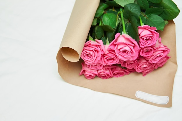 Blumenstrauß aus rosa, frisch geschnittenen Rosen, eingewickelt in schönes Papier und mit Band gebunden