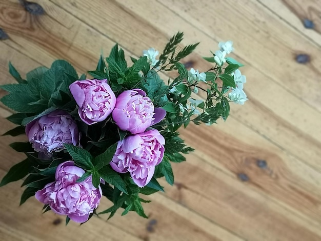 Blumenstrauß aus rosa Pfingstrosen Bündel rosa Pfingstrosen in Vase auf Holzhintergrund