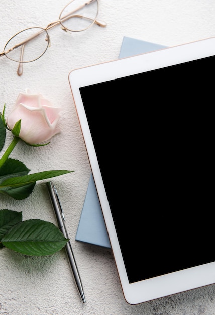 Blumenstrauß aus Rosen und Tablet auf konkretem Hintergrund