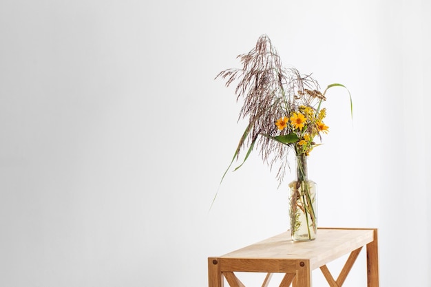 Blumenstrauß aus Schilf und gelben Herbstblumen in der Flasche auf weißem Hintergrund