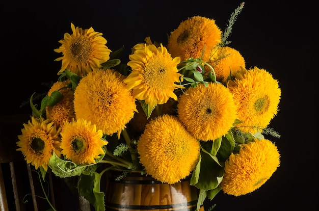 Blumenstrauß aus schönen dekorativen Sonnenblumen auf schwarzem Hintergrund